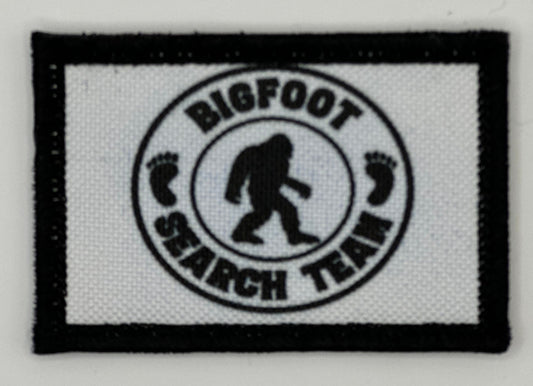 a white and black patch with a bigfoot search team logo