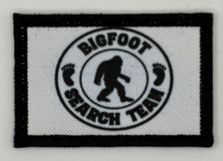 a white and black patch with a bigfoot search team logo