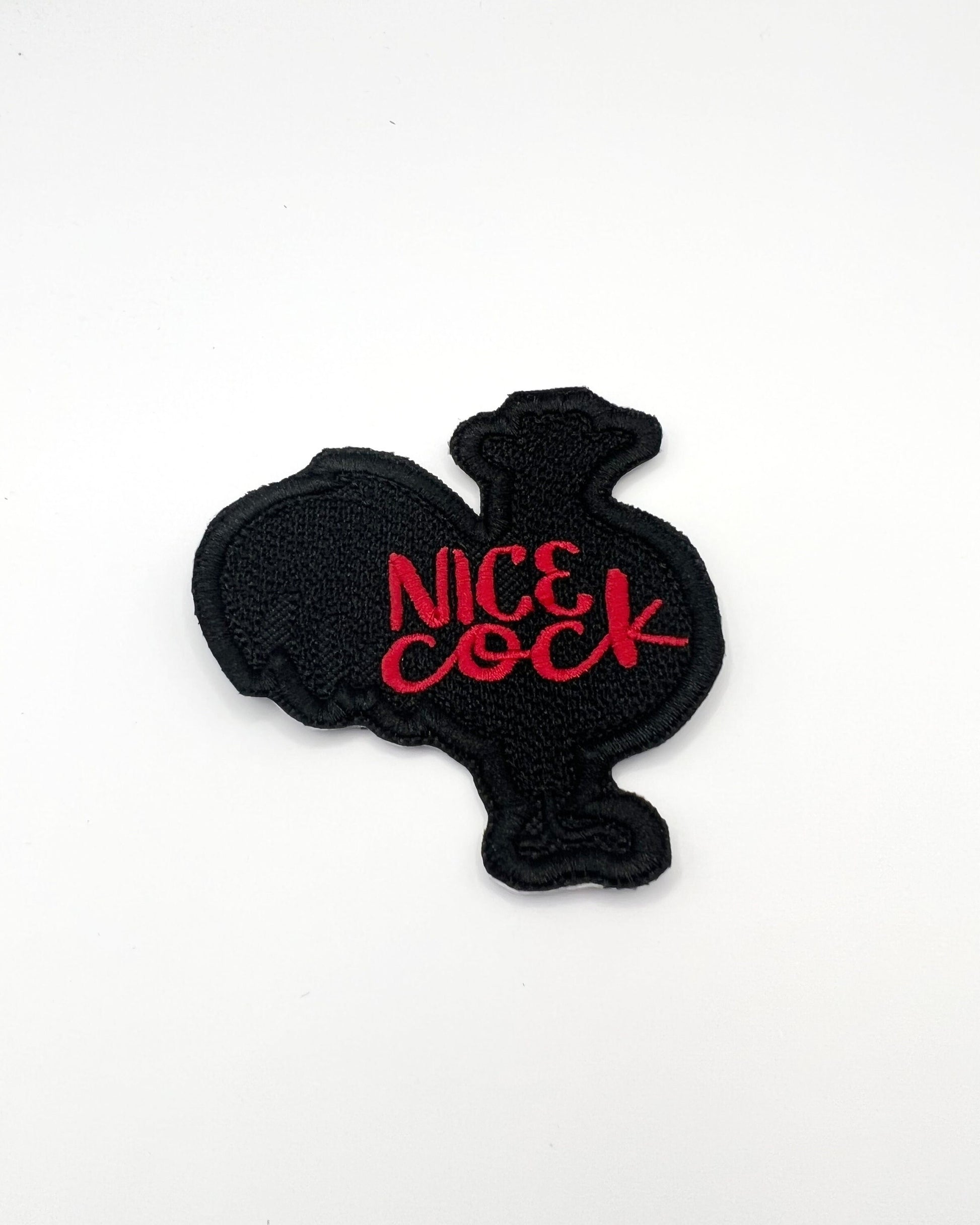 Embroidered patch in the shape of a rooster with the words nice cock in red