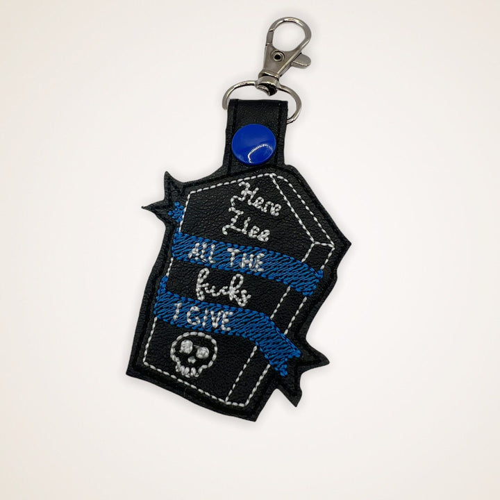 Embroidered Keychain that says Here Lies the Fucks I Give in a coffin shape