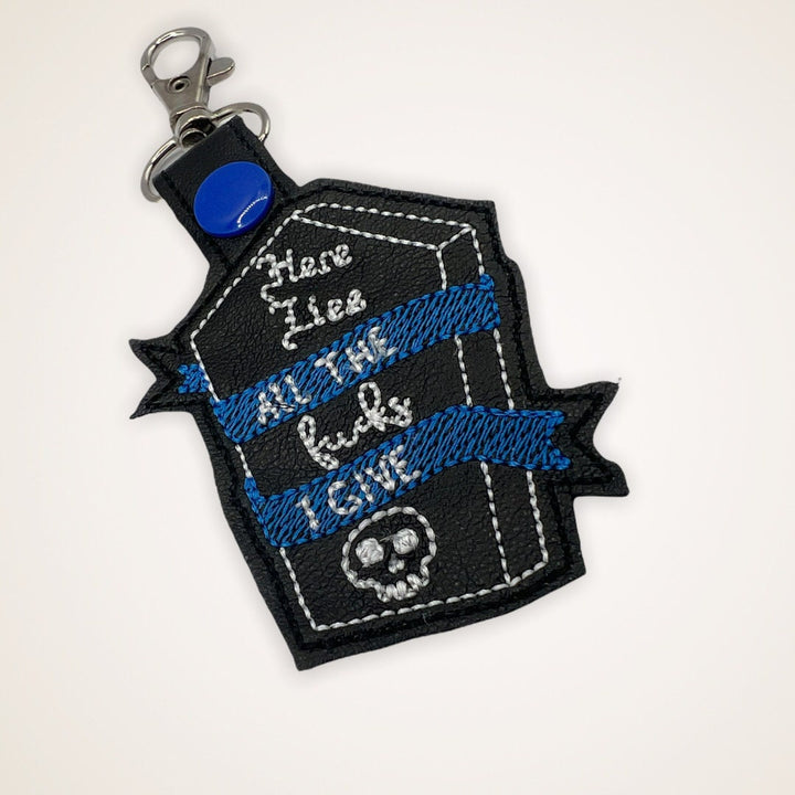 Embroidered Keychain that says Here Lies the Fucks I Give in a coffin shape