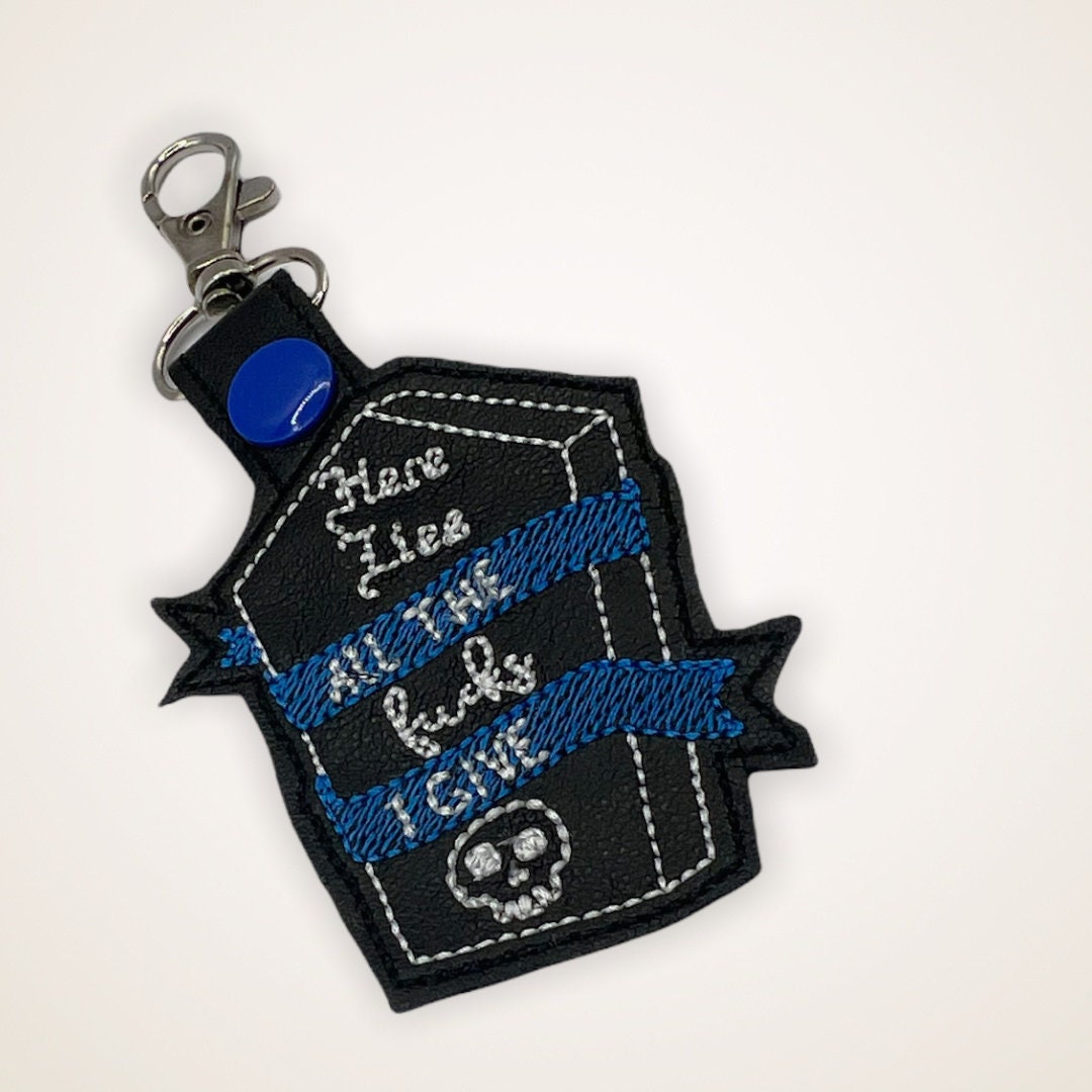 Embroidered Keychain that says Here Lies the Fucks I Give in a coffin shape