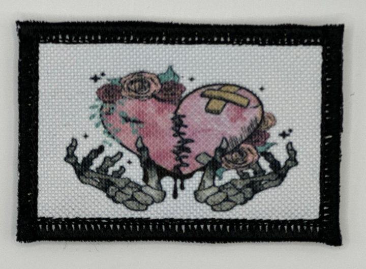 a cross stitch picture of two hands holding a heart