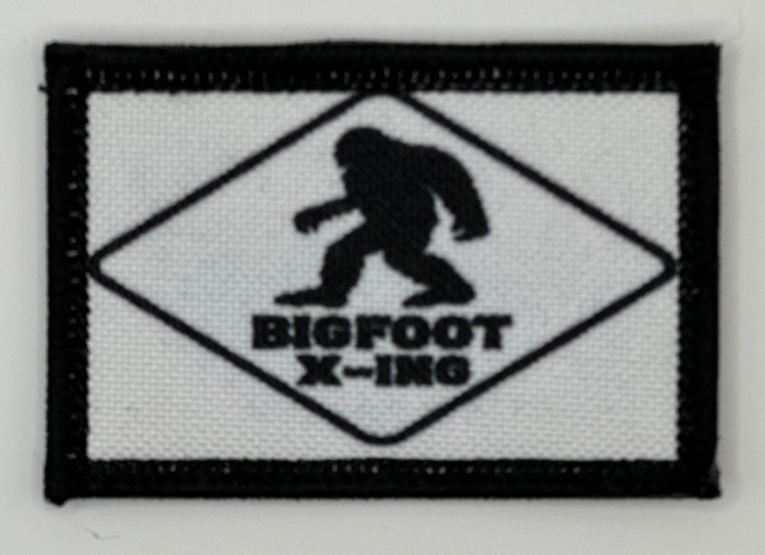 a white and black patch with a bigfoot x - inc logo