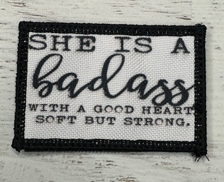 a black and white patch with the words she is a badass with a good